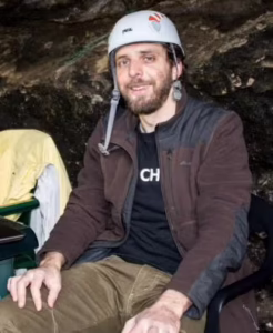 Caley Orr in a cave wearing a caving helmet.