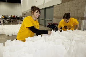 Two female students packing lunch bags at a community event for the homeless